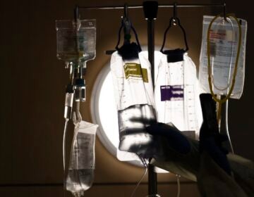 A nurse checks on IV fluids while talking to a patient.