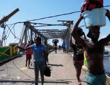 hurricane-melissa-jamaica-2025-10-30 Residents leaving Black River, Jamaica with a damaged bridge behind them
