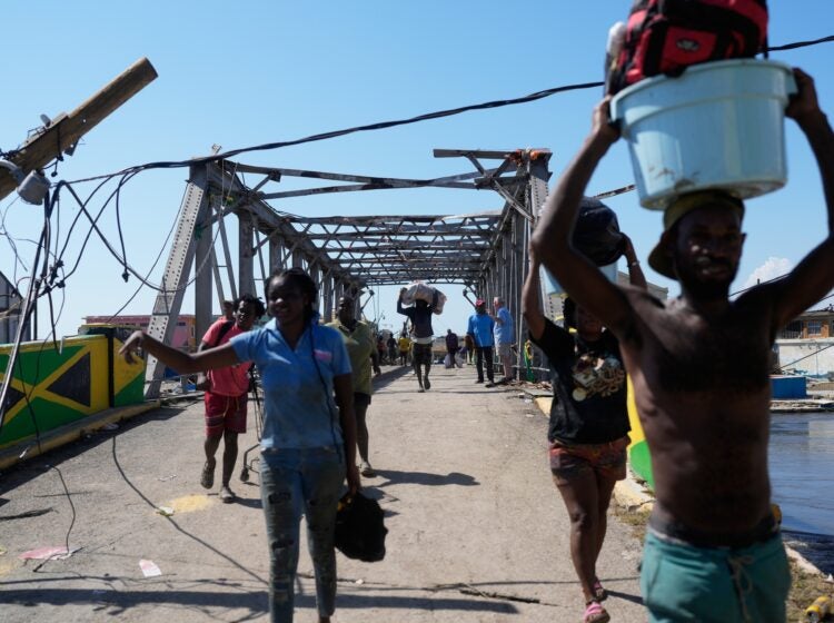 hurricane-melissa-jamaica-2025-10-30 Residents leaving Black River, Jamaica with a damaged bridge behind them