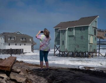 A person stands and takes photos of houses