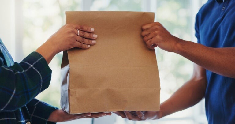 Hands, package and paper bag as delivery with customer or client order, parcel and courier. People, shopping and online with service at postal address or workplace as employee in retail and together A paper bag being handed over in a store