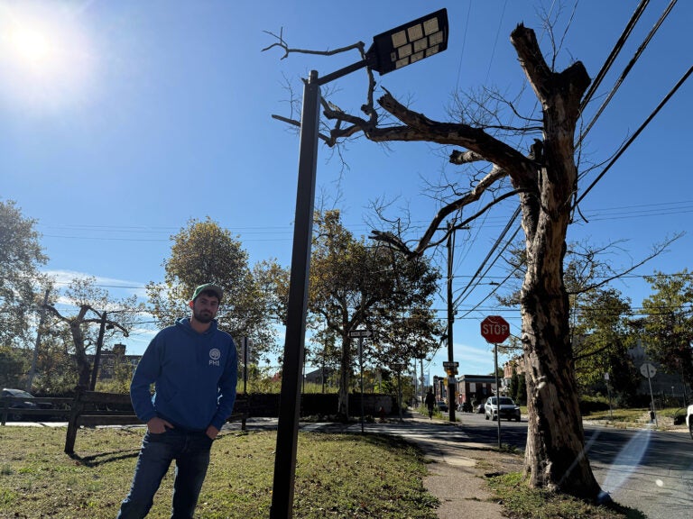 philadelphia-solar-streetlight A man stands underneath a solar-powered streetlight