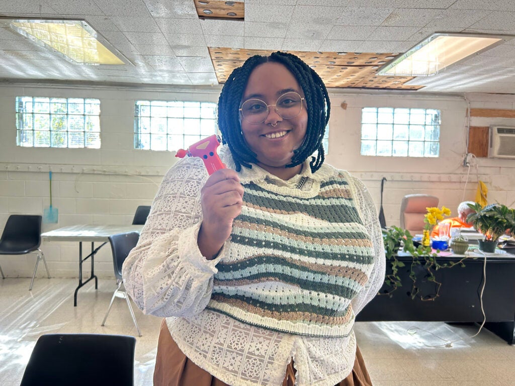 Taylor Quinland, project manager for place-based initiatives with Philadelphia's Office of Sustainability, holds a tool that can break a car window and cut a seat belt in an emergency