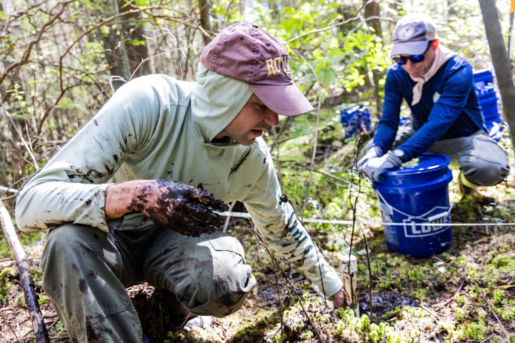 Charles Schutte, an assistant professor at Rowan University’s Department of Environmental Science, packs dirt along the edges of a well in an Atlantic white cedar swamp in the Wharton State Forest while Joshua Moody, a researcher at the NJDEP Division of Science and Research, waits to add bentonite.