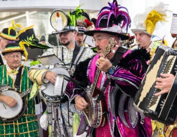 Members of various Mummers clubs’ string bands play their instruments in colorful outfits