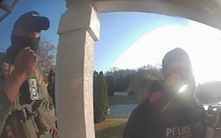 2 masked officers shown from the view of a door camera