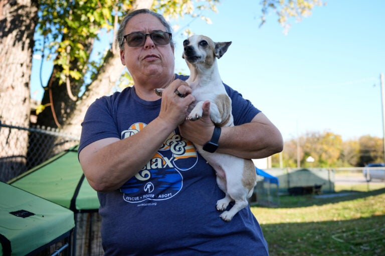 A woman holds a small dog