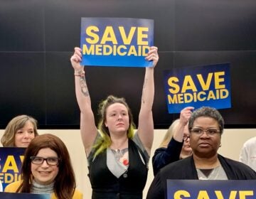 a woman in a crowd holds a sign reading SAVE MEDICAID
