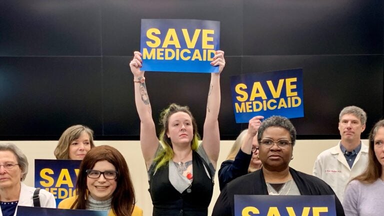 a woman in a crowd holds a sign reading SAVE MEDICAID