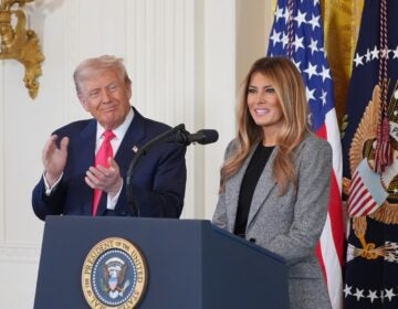 President Donald Trump listens as first lady Melania Trump speaks