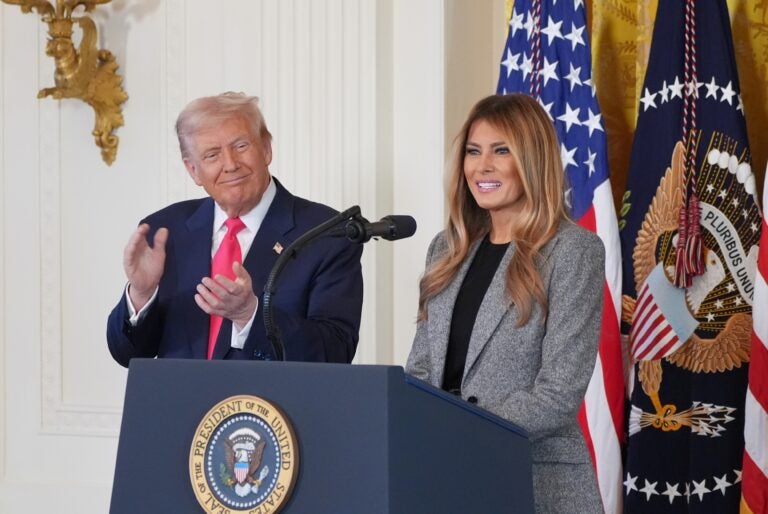 President Donald Trump listens as first lady Melania Trump speaks