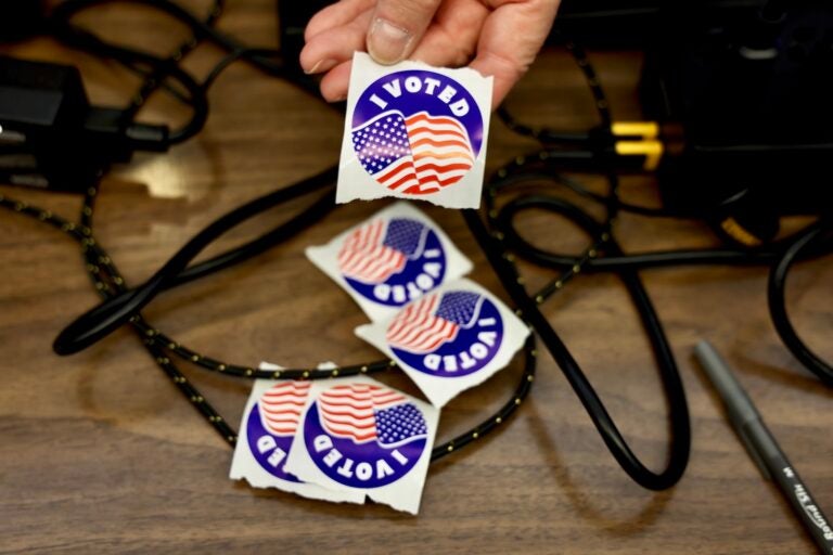 An election worker offers stickers to voters at the Moorestown Township Fire Station.