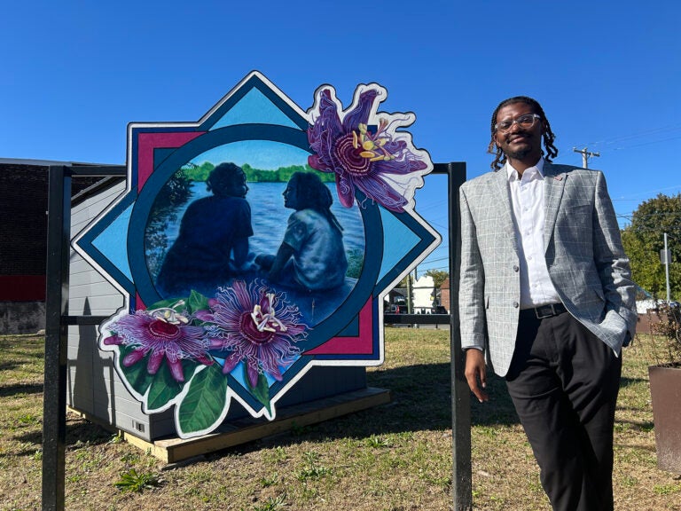Isaiah T. Martin, Empowered CDC’s president and CEO, stands next to a piece of artwork at the nonprofit's first community waste disposal site near Bartram's Garden.