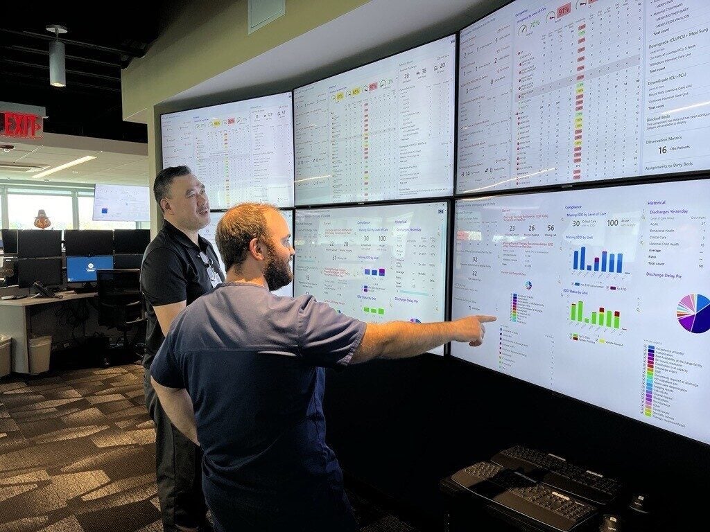 Two workers look at screens