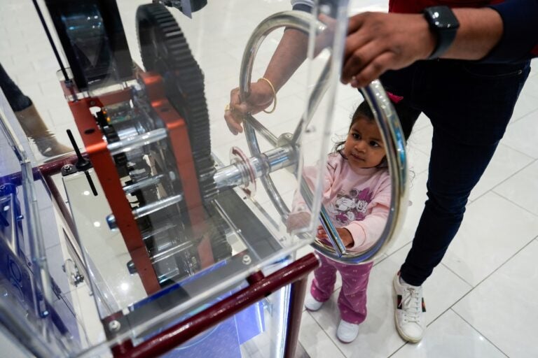 A girl and a parent use a penny press machine