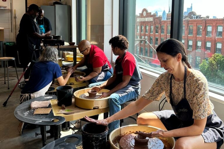 Participants learning clay techniques on pottery wheels