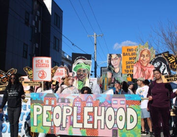 peoplehood-parade-25-10 People participating in a parade in West Philadelphia hold up a sign that reads