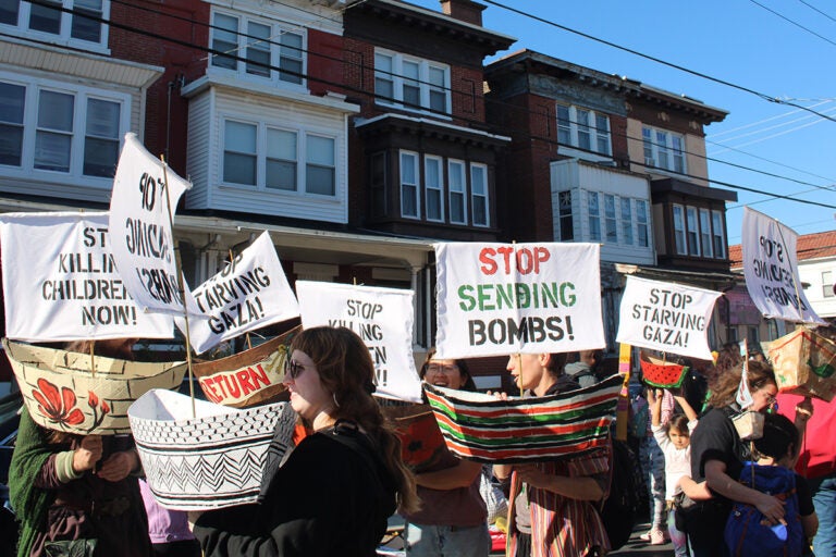 People hold various signs as they march in the 25th annual Peoplehood Parade in West Philadelphia