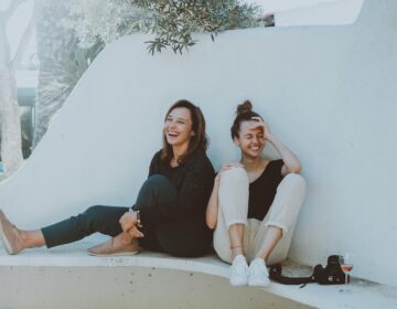 Two women sitting on a white bench. (Elle Hughes)