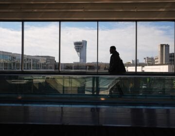 A traveler moves in view of a control tower at Philadelphia International Airport in Philadelphia