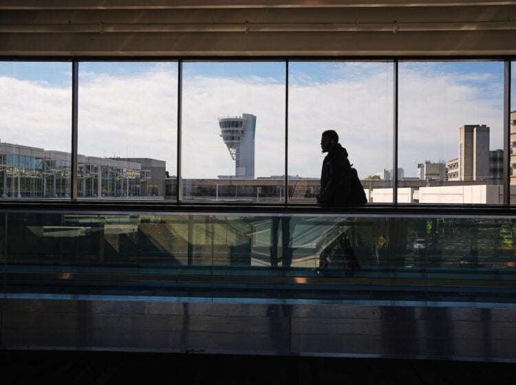 A traveler moves in view of a control tower at Philadelphia International Airport in Philadelphia
