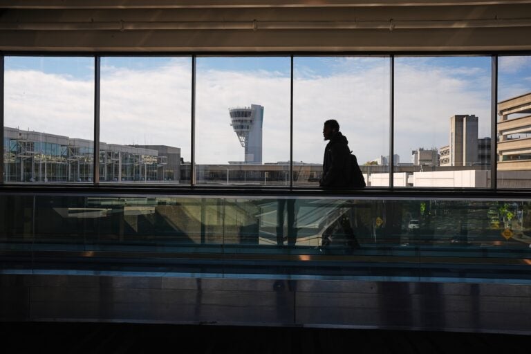 A traveler moves in view of a control tower at Philadelphia International Airport in Philadelphia