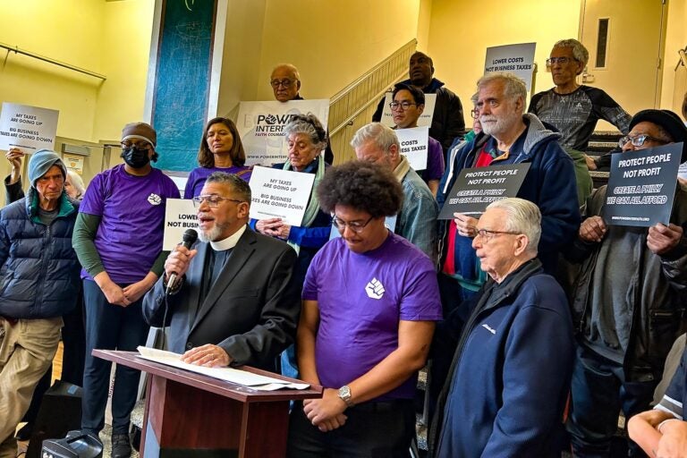 Rev. Gregory Edwards speaking at the podium surrounded by other people
