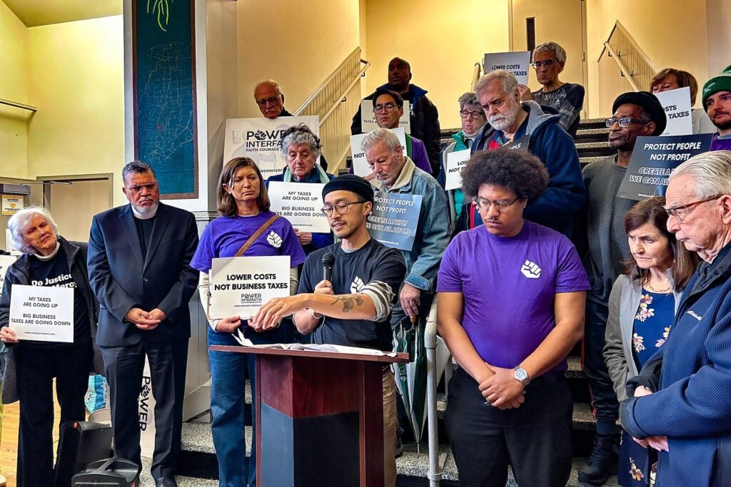 An Tran speaking at the podium surrounded by other people