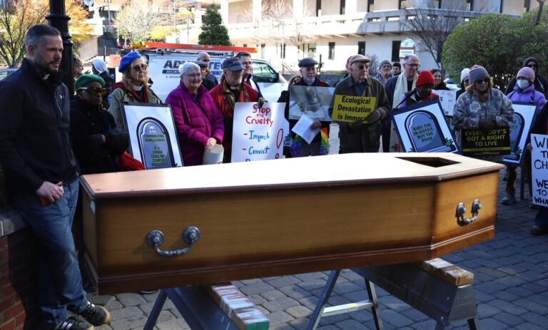 Protesters standing behind a large coffin.
