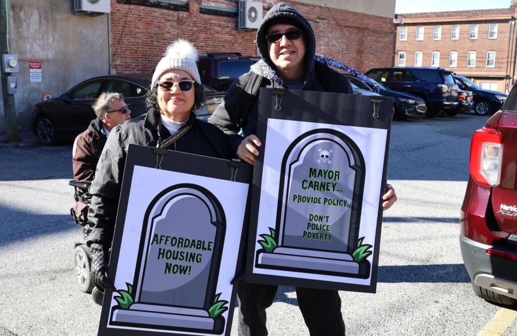 Two people at the protest holding up signs featuring gravestones
