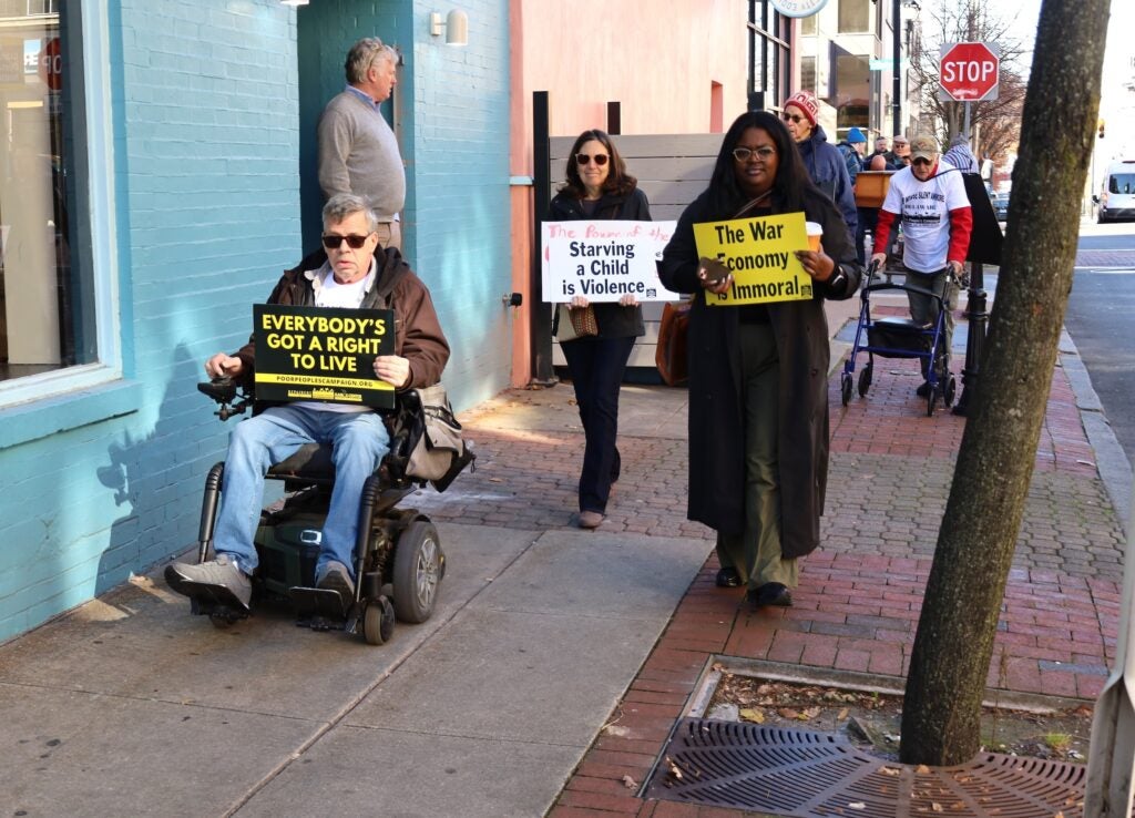People marching on the sidewalk and holding up signs