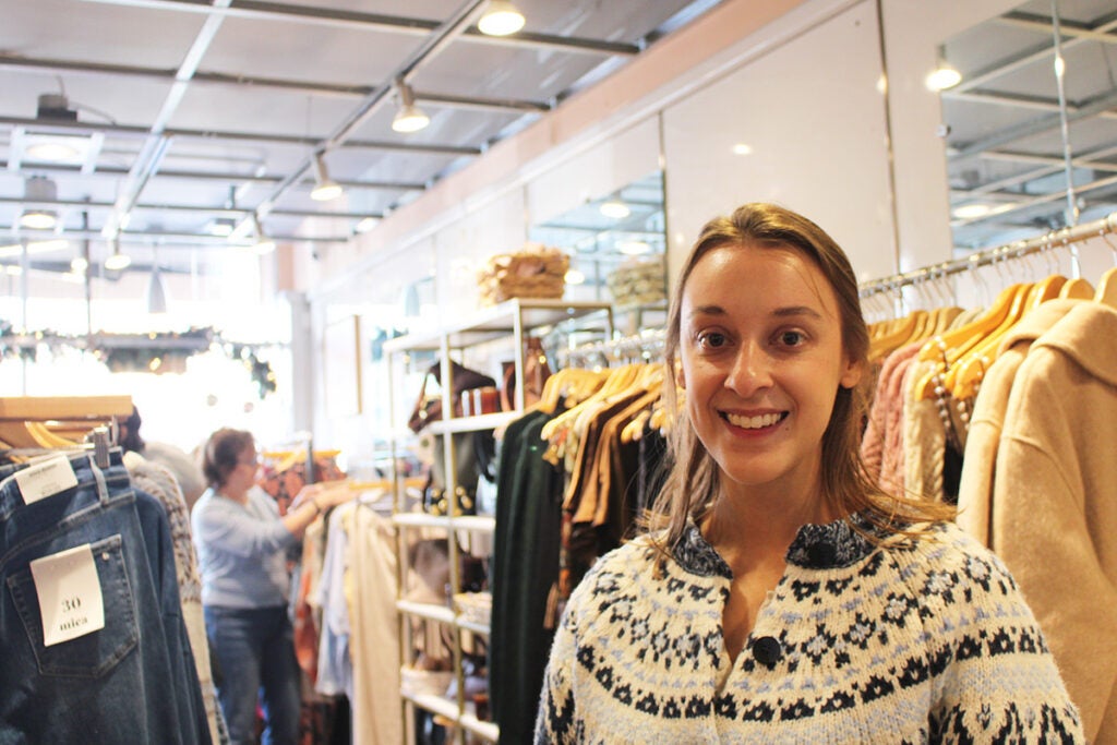 Kristina Gaglianese, the owner of August Moon Boutique, smiles at the camera in front of racks of clothes