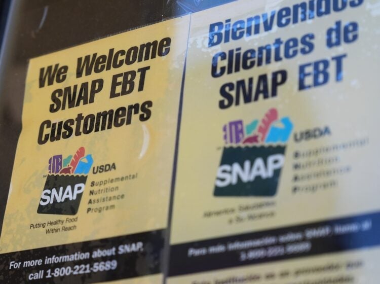 A sign with SNAP EBT information is posted on a store window