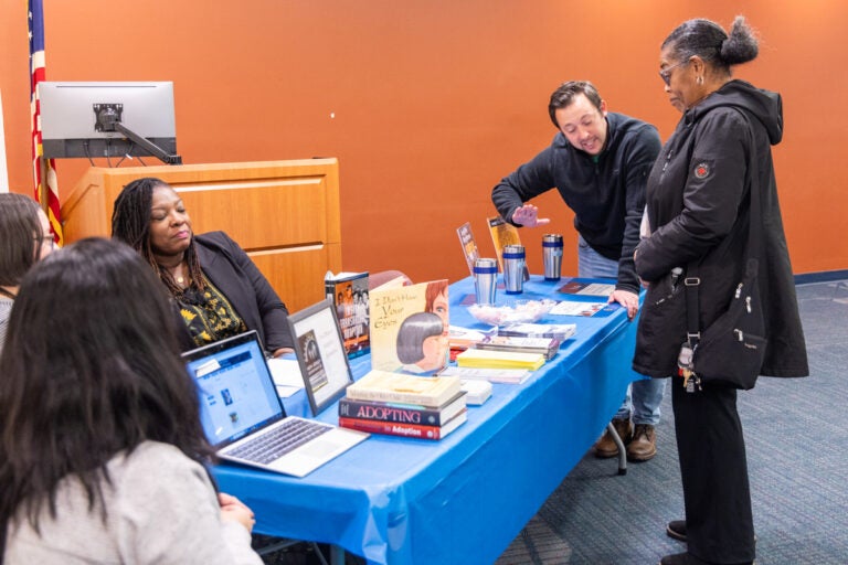 A women gets information from people sitting at a table with information