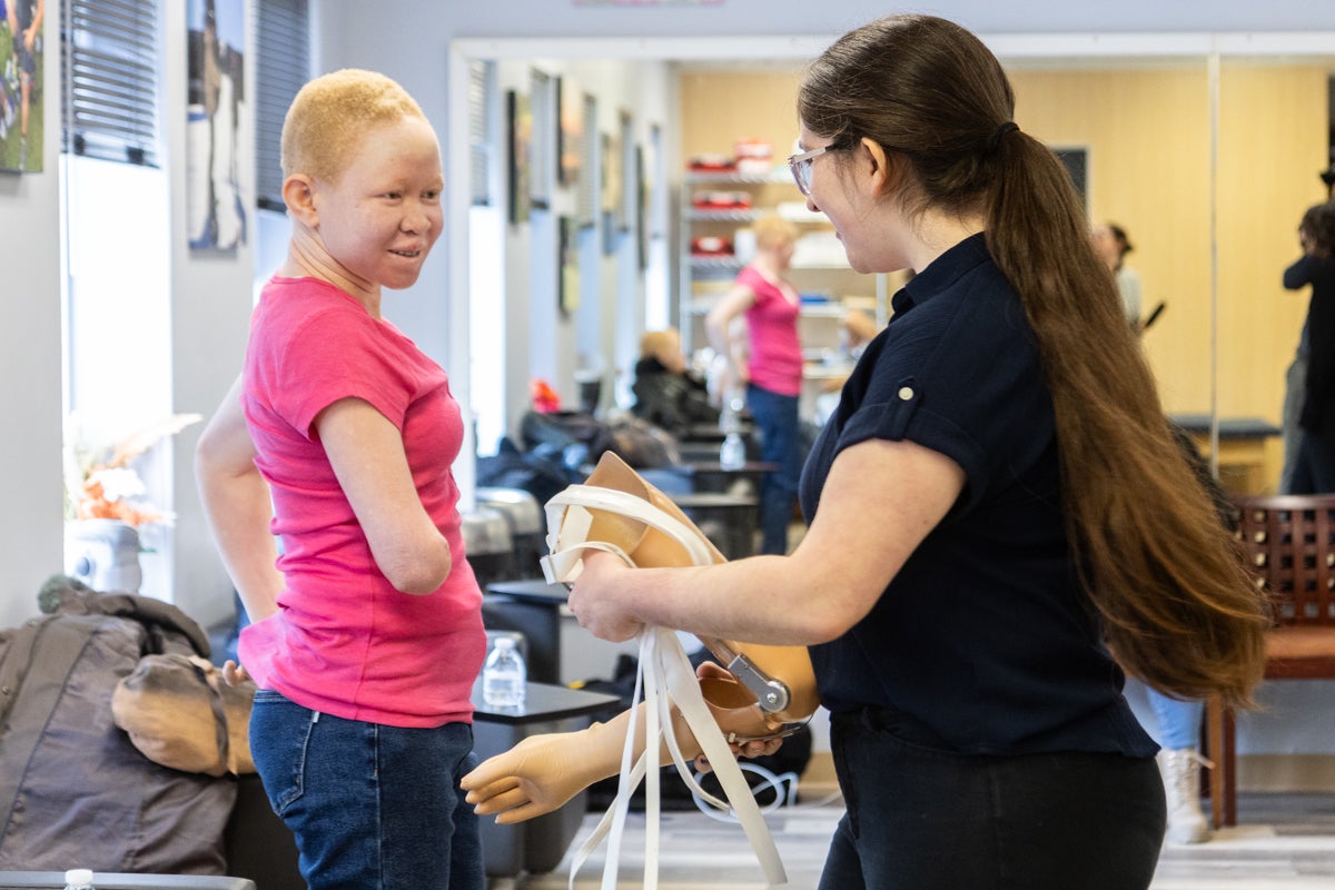 A doctor is holding on to the new prosthetic right arm on Pendo, who is looking down