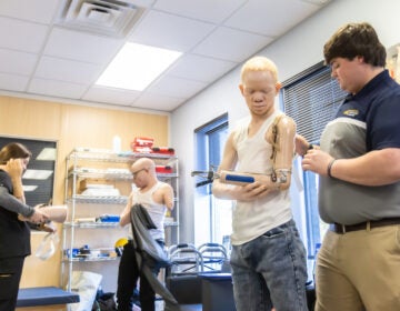 Mwigulu and Emmanuel getting set up with new prosthetic arms from students