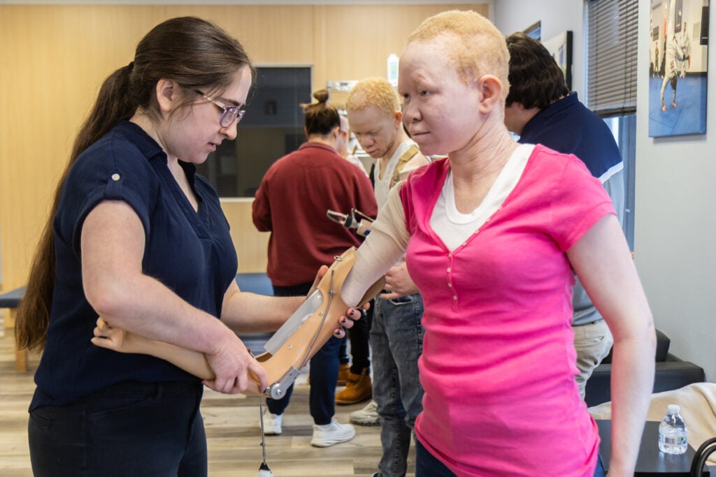 A doctor is holding on to the new prosthetic right arm on Pendo, who is looking down