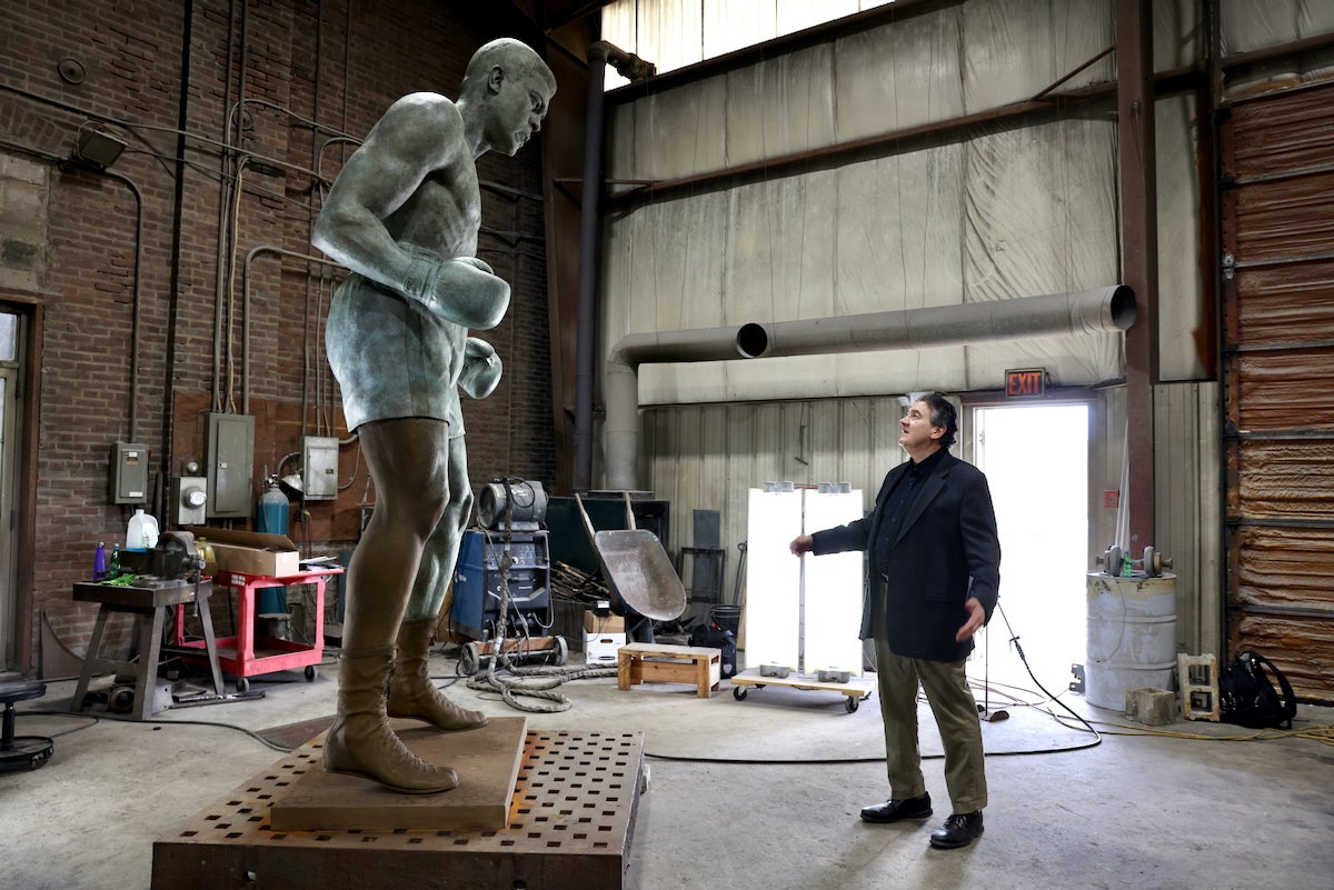 Zenos Frudakis looks up at a 10-foot-tall statue of Muhammad Ali inside a large open space at Laran Bronze Foundry in Chester, Pa.