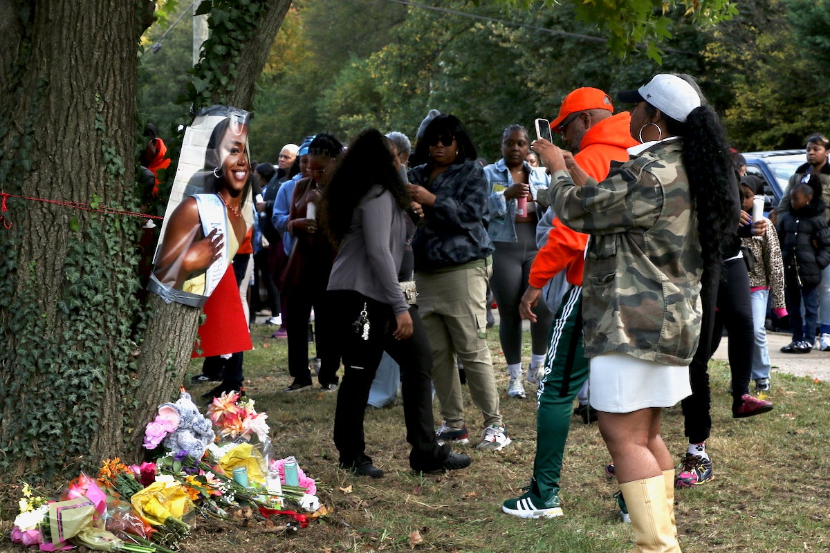 Family members and community members are paying tribute to Kada Scott with a candlelight vigil outside of Ada H. Lewis Middle School in Philadelphia. A large photo of Scott is attached to a tree, and many flowers are placed at its foot.