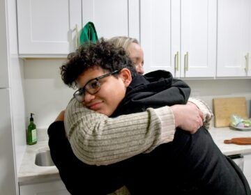 A mother and son embrace for a hug in their kitchen