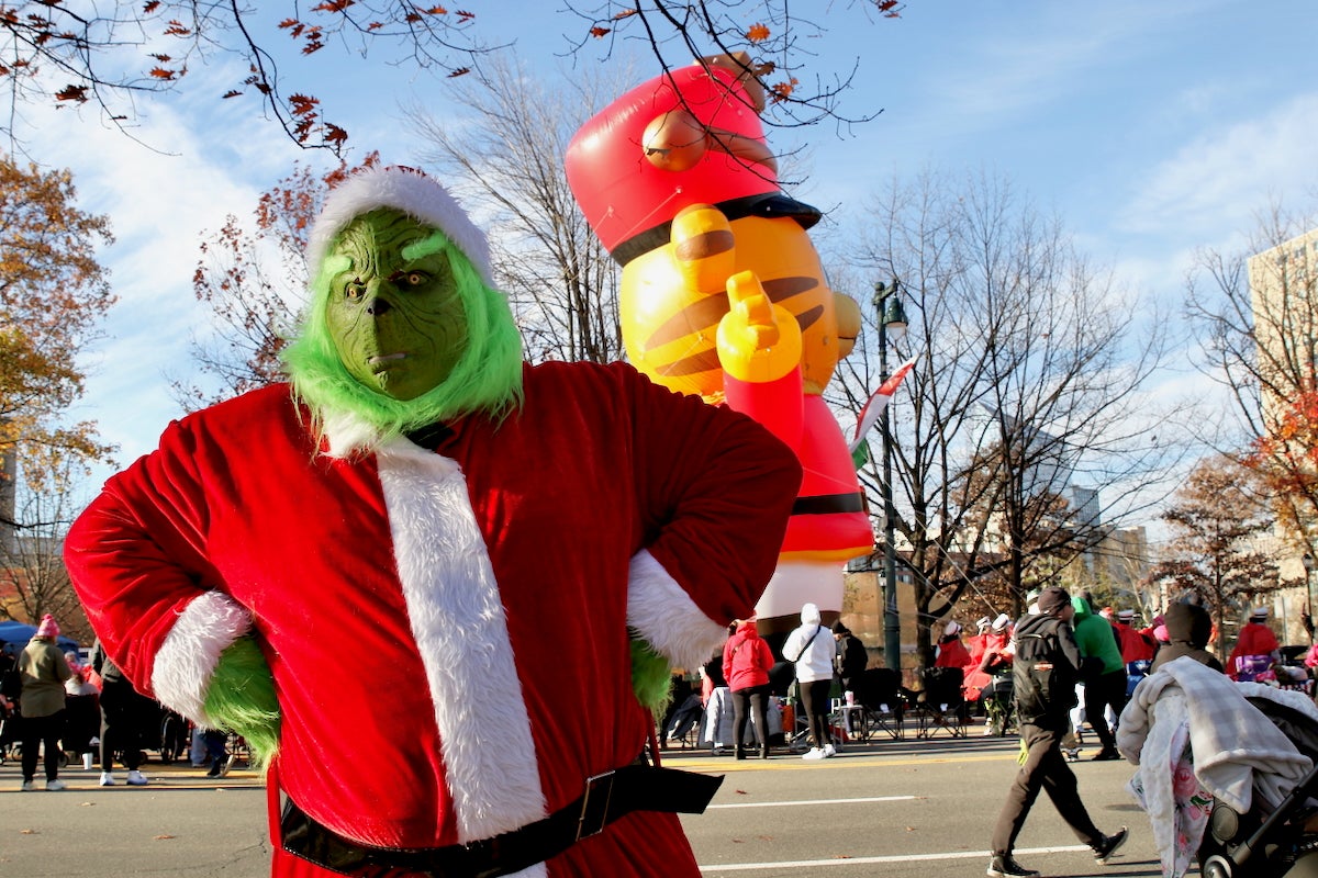 A performer dressed in costume as the Grinch character poses for a photo during Philadelphia's Thanksgiving Parade on Benjamin Franklin Parkway.