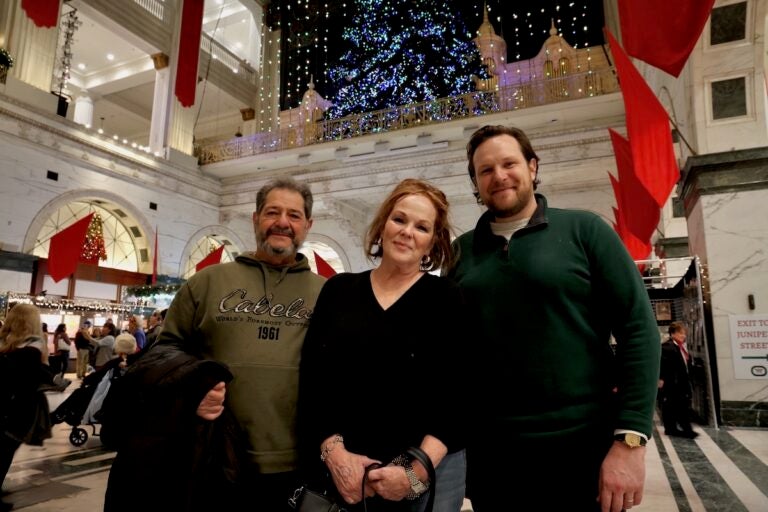 Family poses for photo at the Christmas light show inside the Wanamaker Building