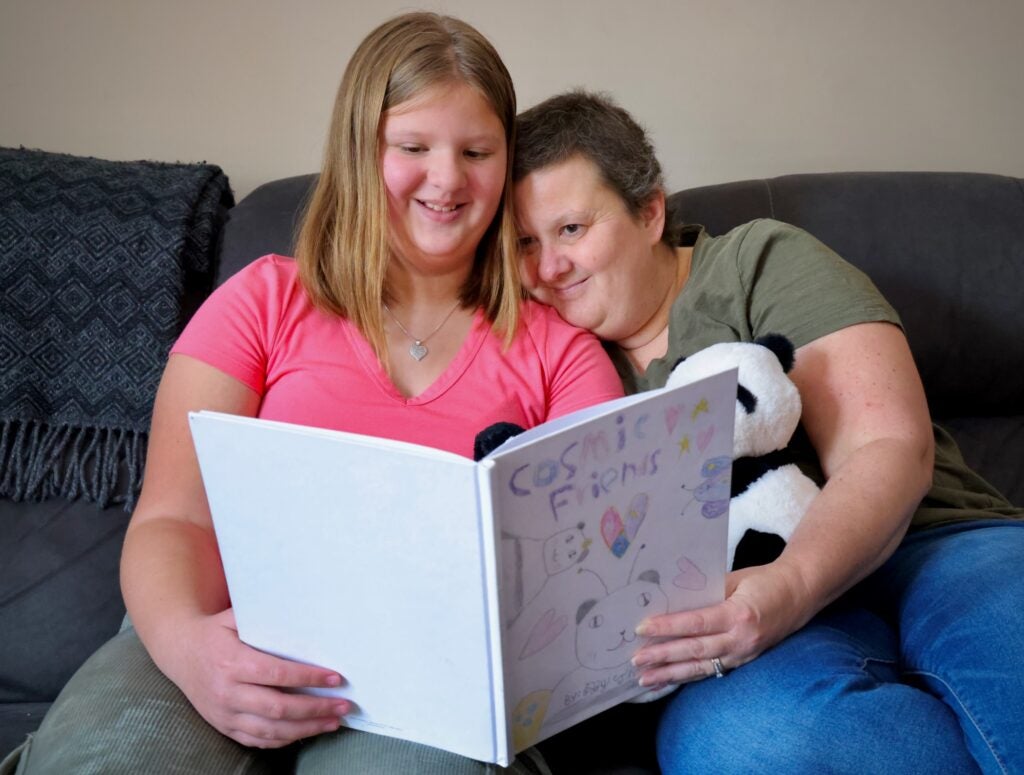 Lizzy Thomas, 10, and her mom, Yvonne, look through the book that Lizzy wrote and illustrated