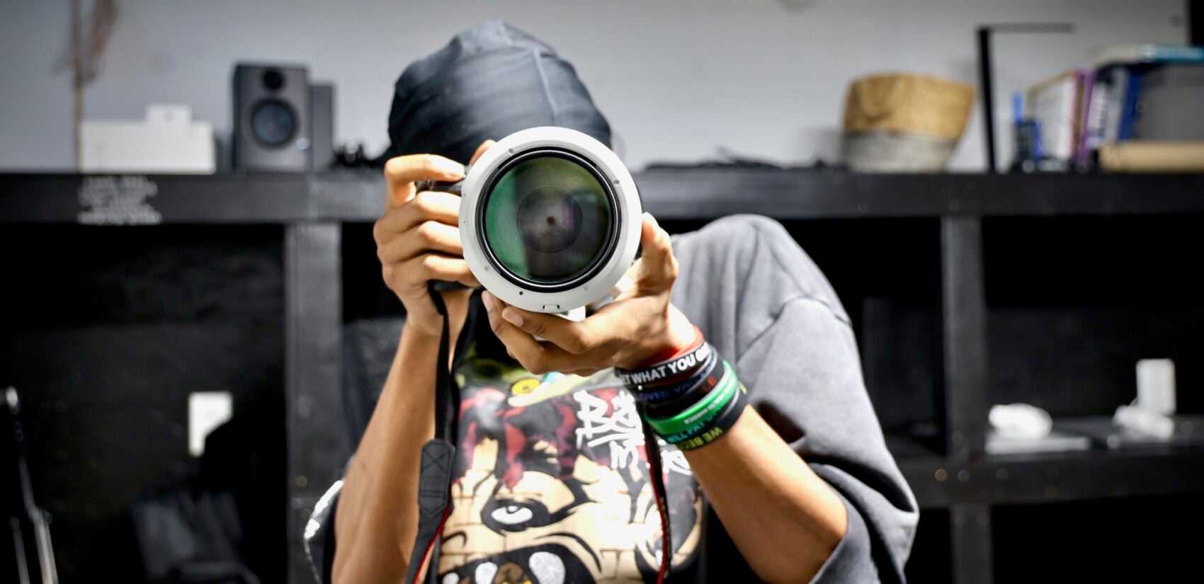 Musheer Daniel looking through a camera lense that is pointed right at the viewer