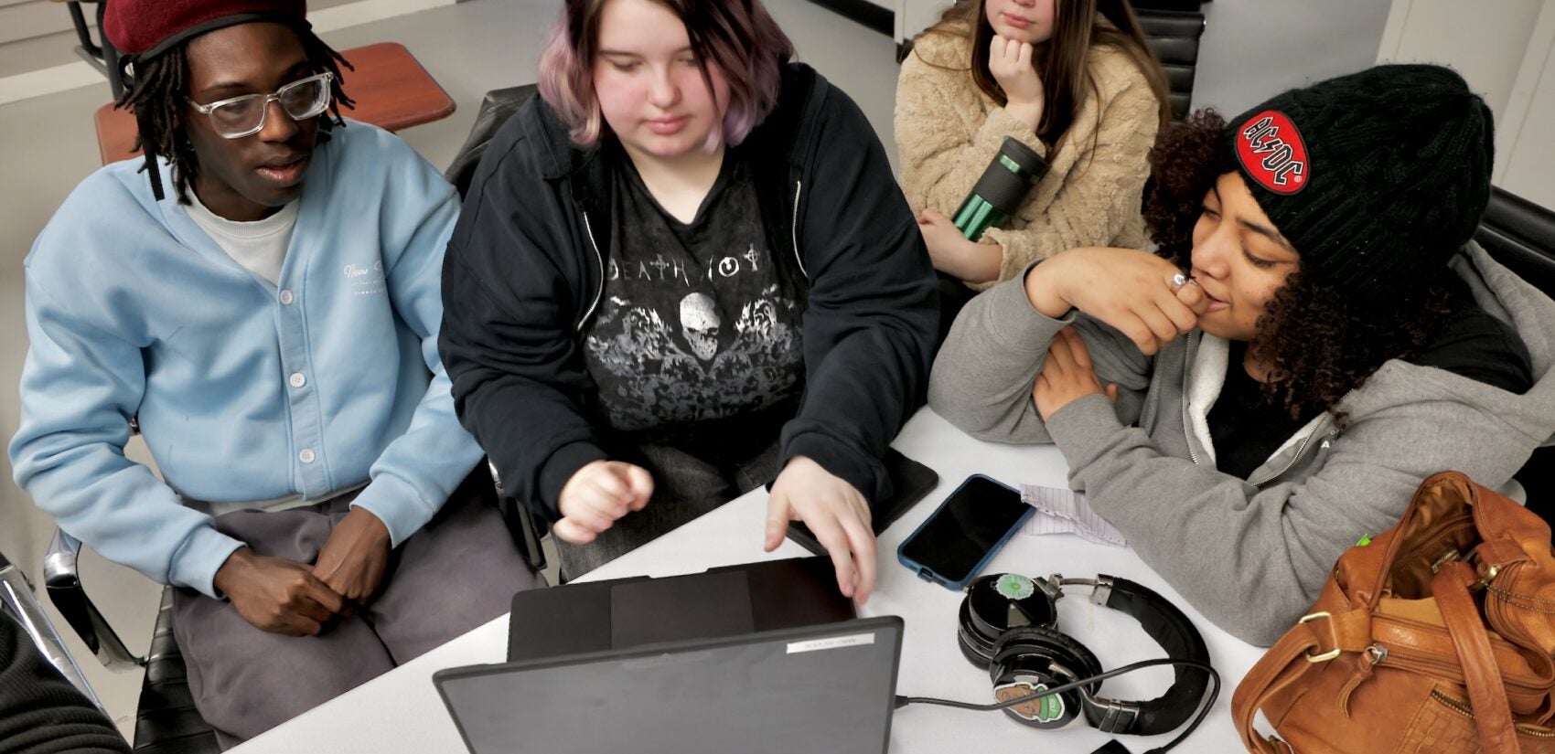 Royce Hall, Morgan Russell, Hyleah Russell and Nialani Morales are sitting together at a table, all looking intently at a laptop computer
