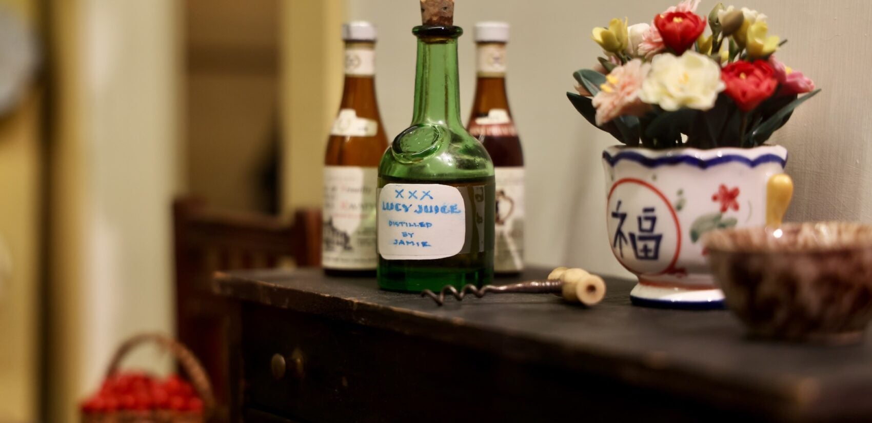 A tiny bottle labeled ''Lucy Juice'' is seen in a dollhouse