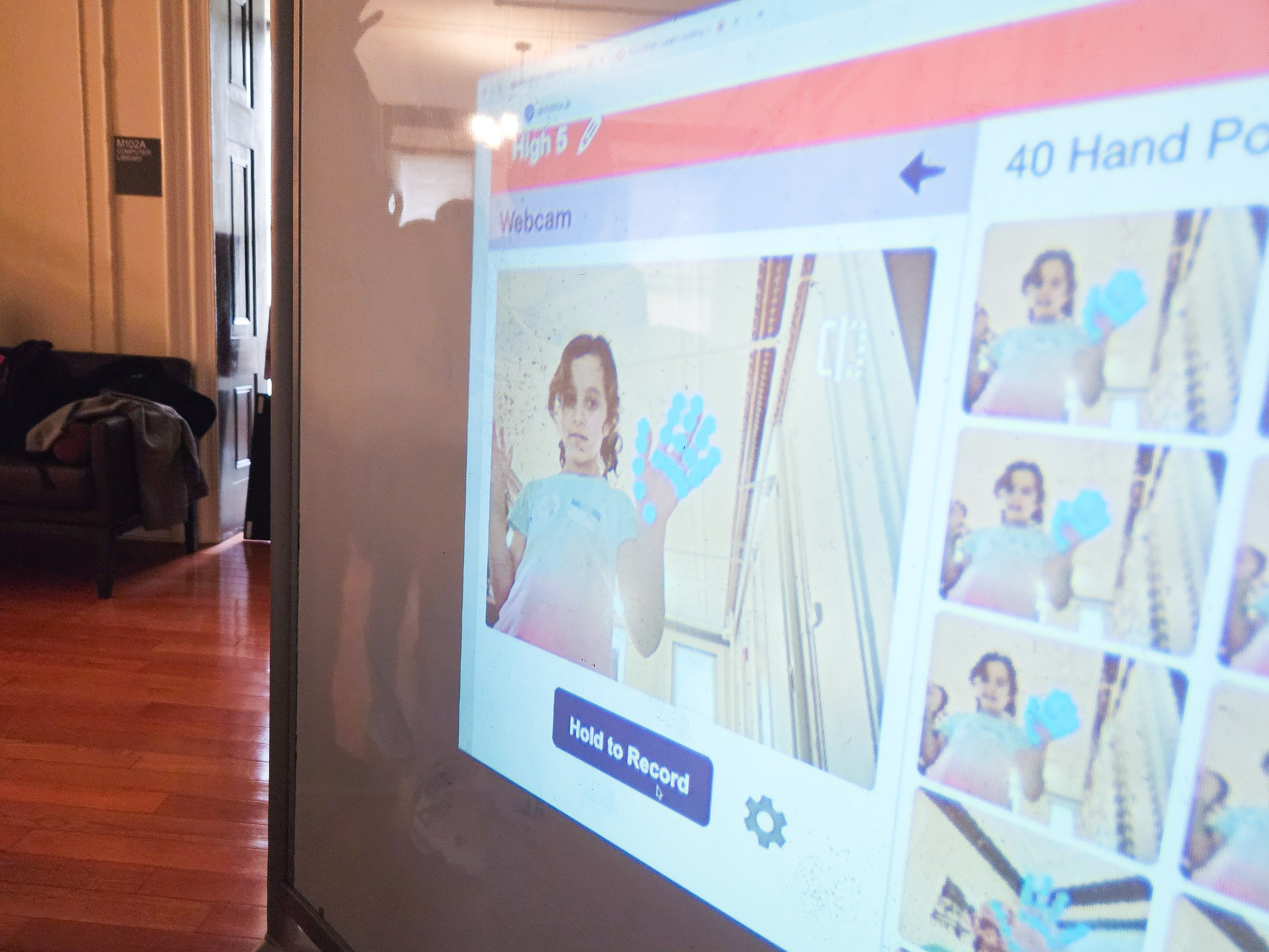 a child holds a hand pose in front of a webcam