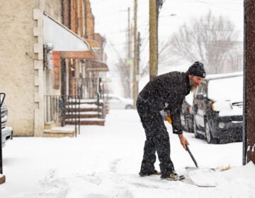 Kevin Gallagher shoveling snow from the sidewalk in front of his home during a snowstorm