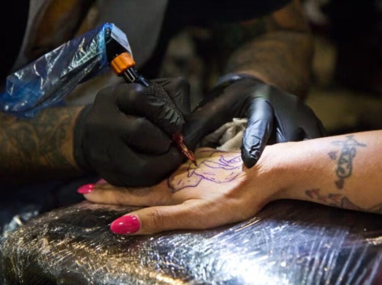 A rose being tattooed onto a hand