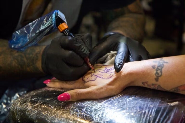 A rose being tattooed onto a hand